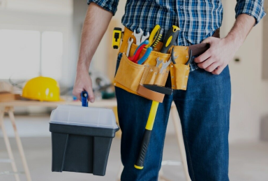 Um homem com uma maleta na mão e um cinto com ferramentas.